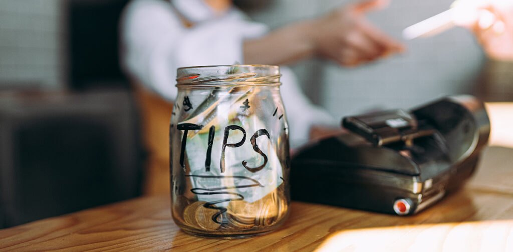 A tip jar located on a counter next to a cashier.
