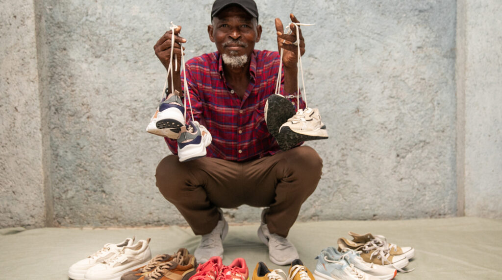 Roosevelt poses with shoes as he earns a living through the reuse economy.